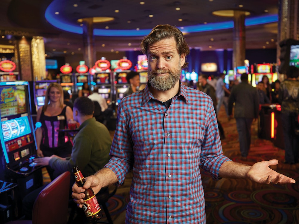 Man standing at a casino in front of slot machines and table games