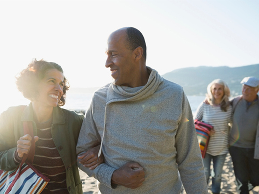 Active adult couple walking on the beach with friends