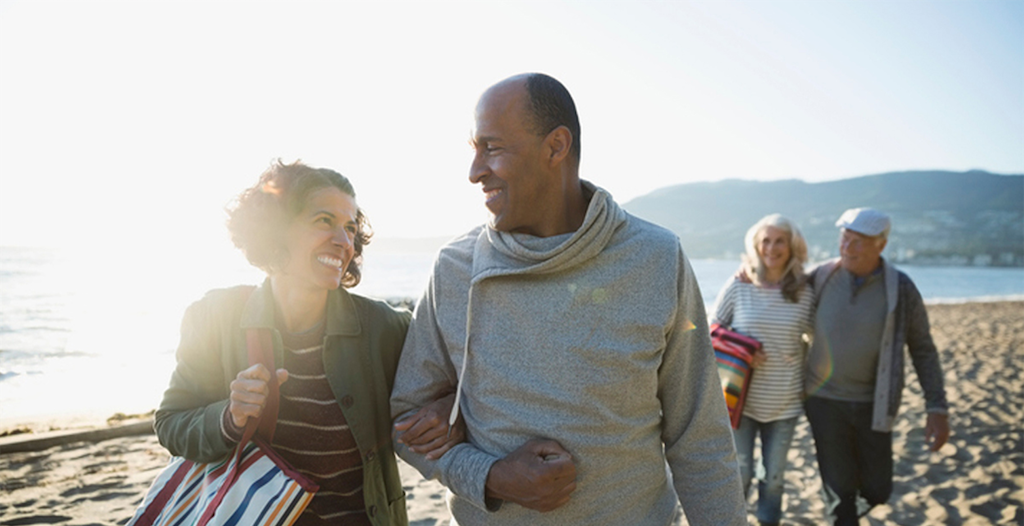 Active adult couple walking on the beach with friends